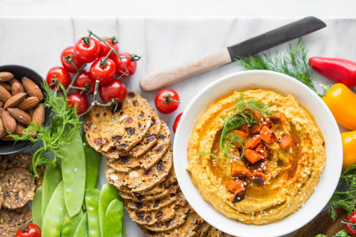 Hummus spread on marble with various vegetables