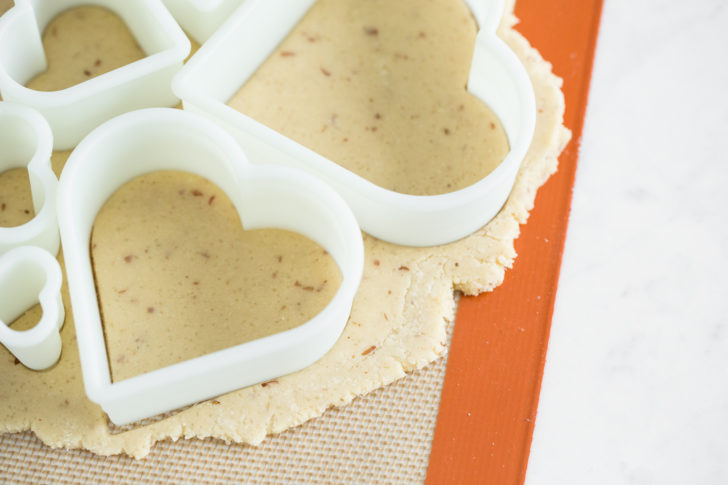 sugar cookies batter being cut with heart shapes